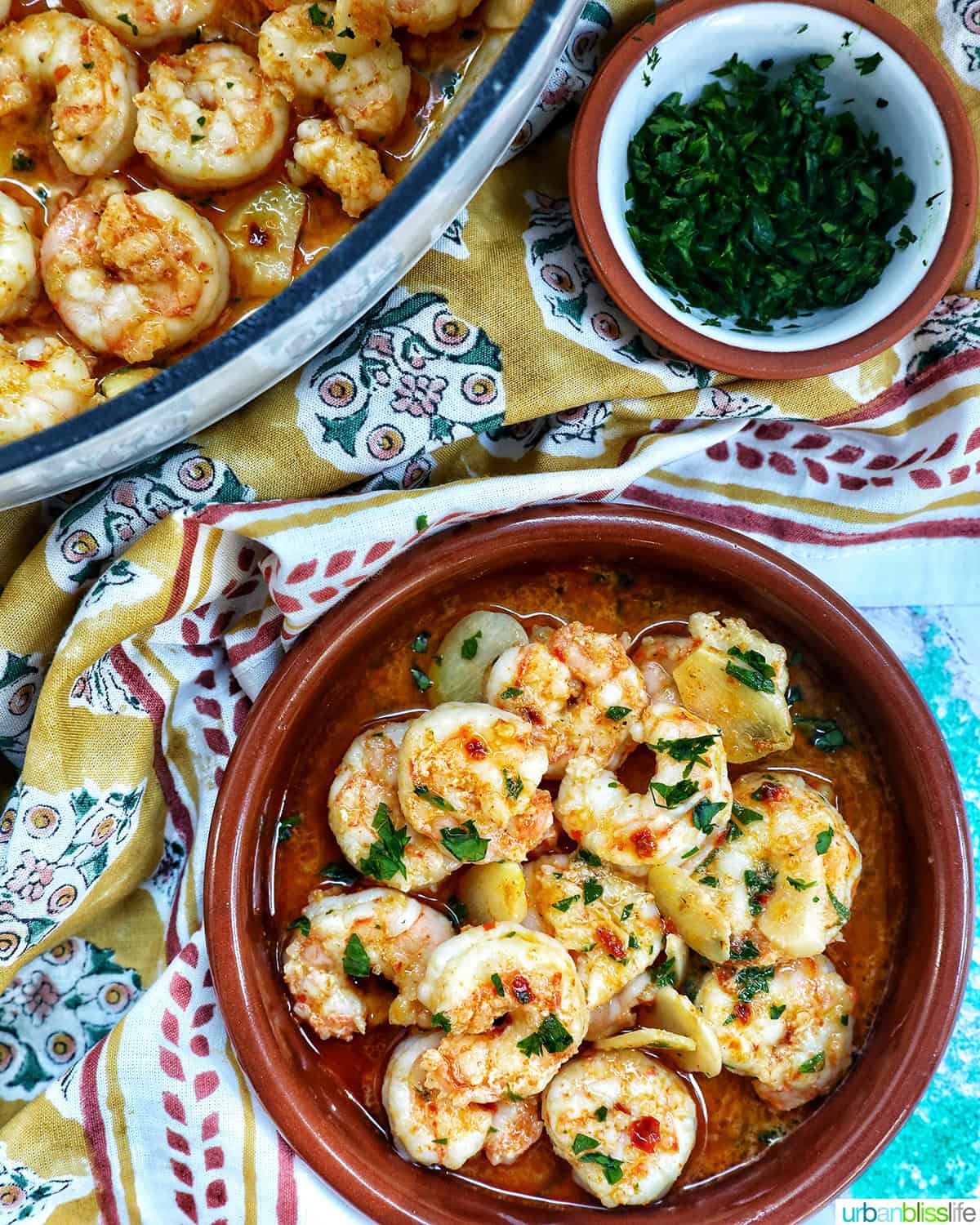 Spanish prawns with garlic (gambas al ajillo) in Spanish cazuelas clay dishes with side of chopped parsley.