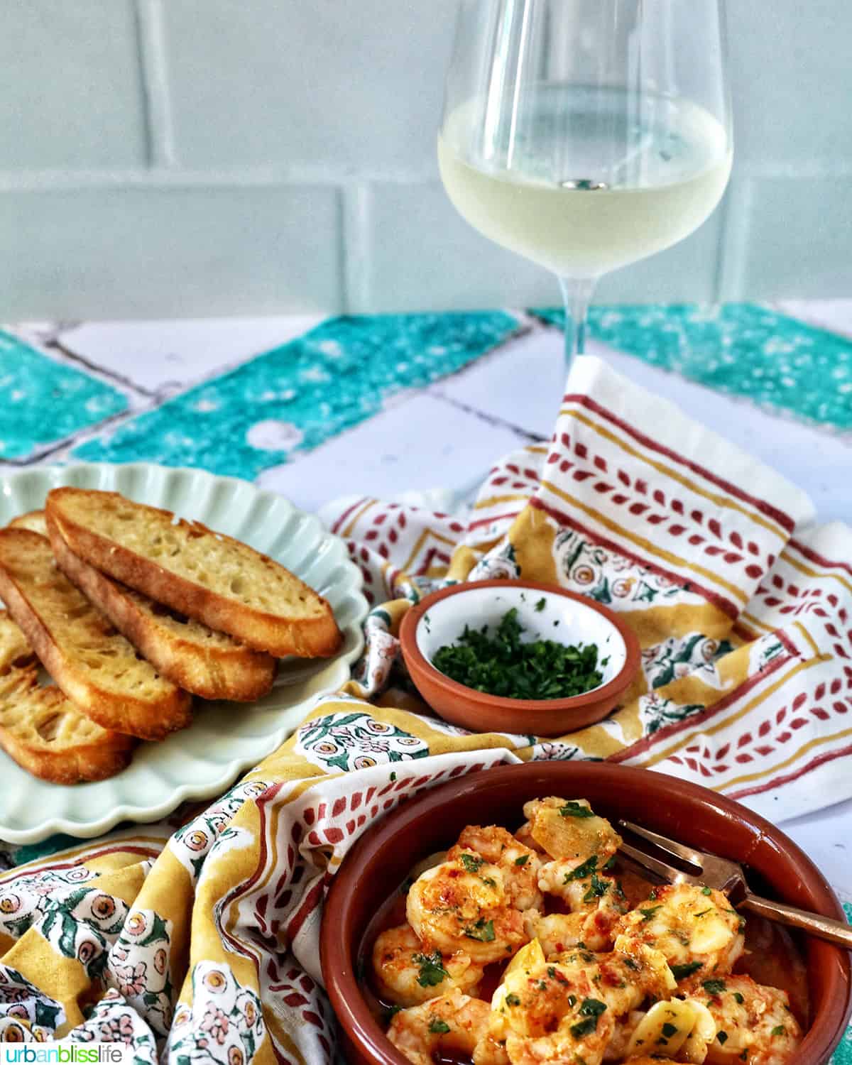 gambas al ajillo with glass of white wine and sliced baguette.