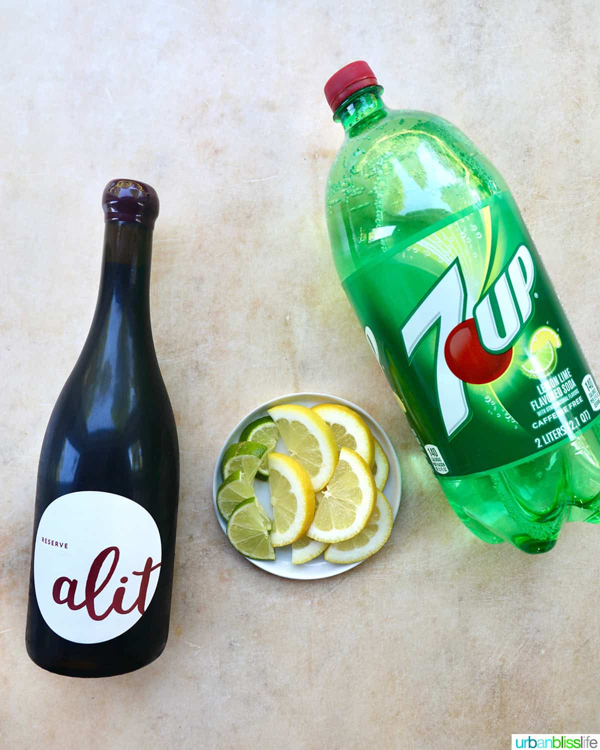 bottle of red wine, bottle of lemon lime soda, plate with lemon and lime slices.