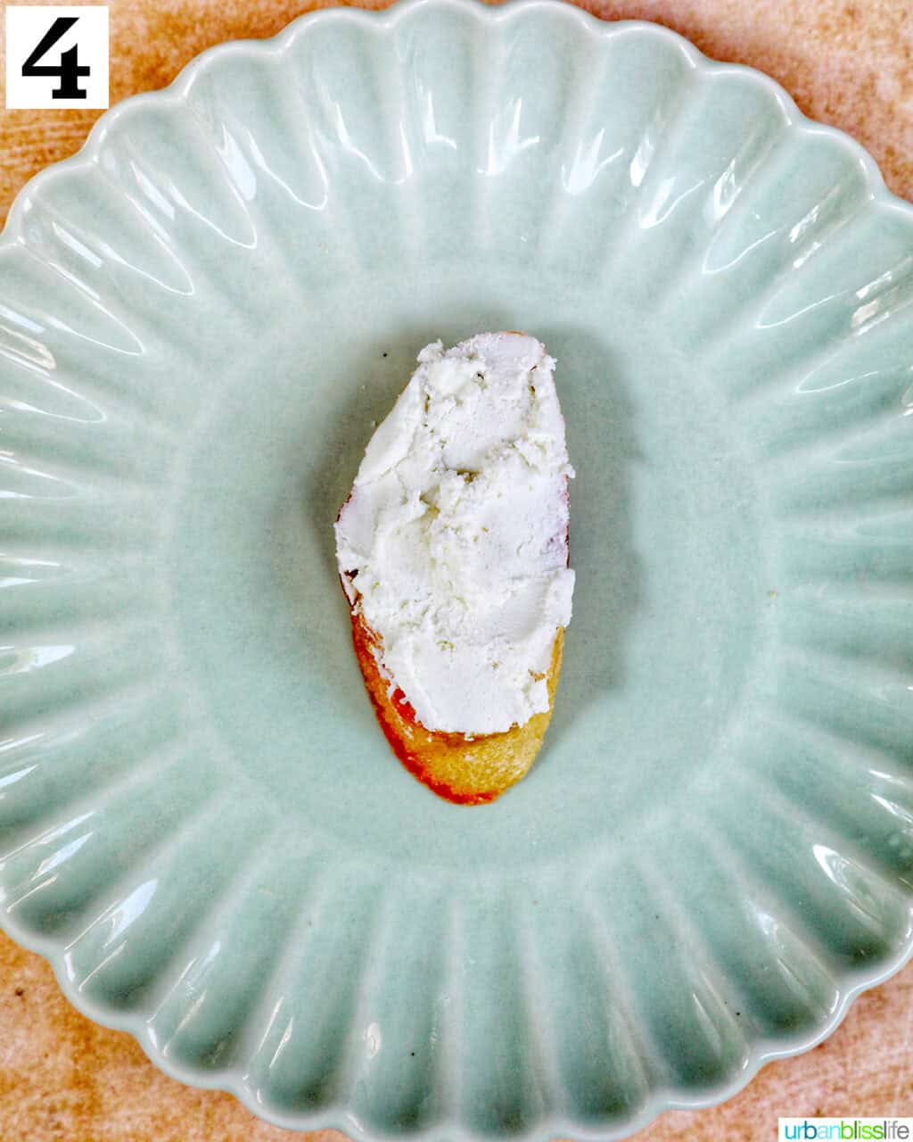 goat cheese on a crostini slice on a green plate.