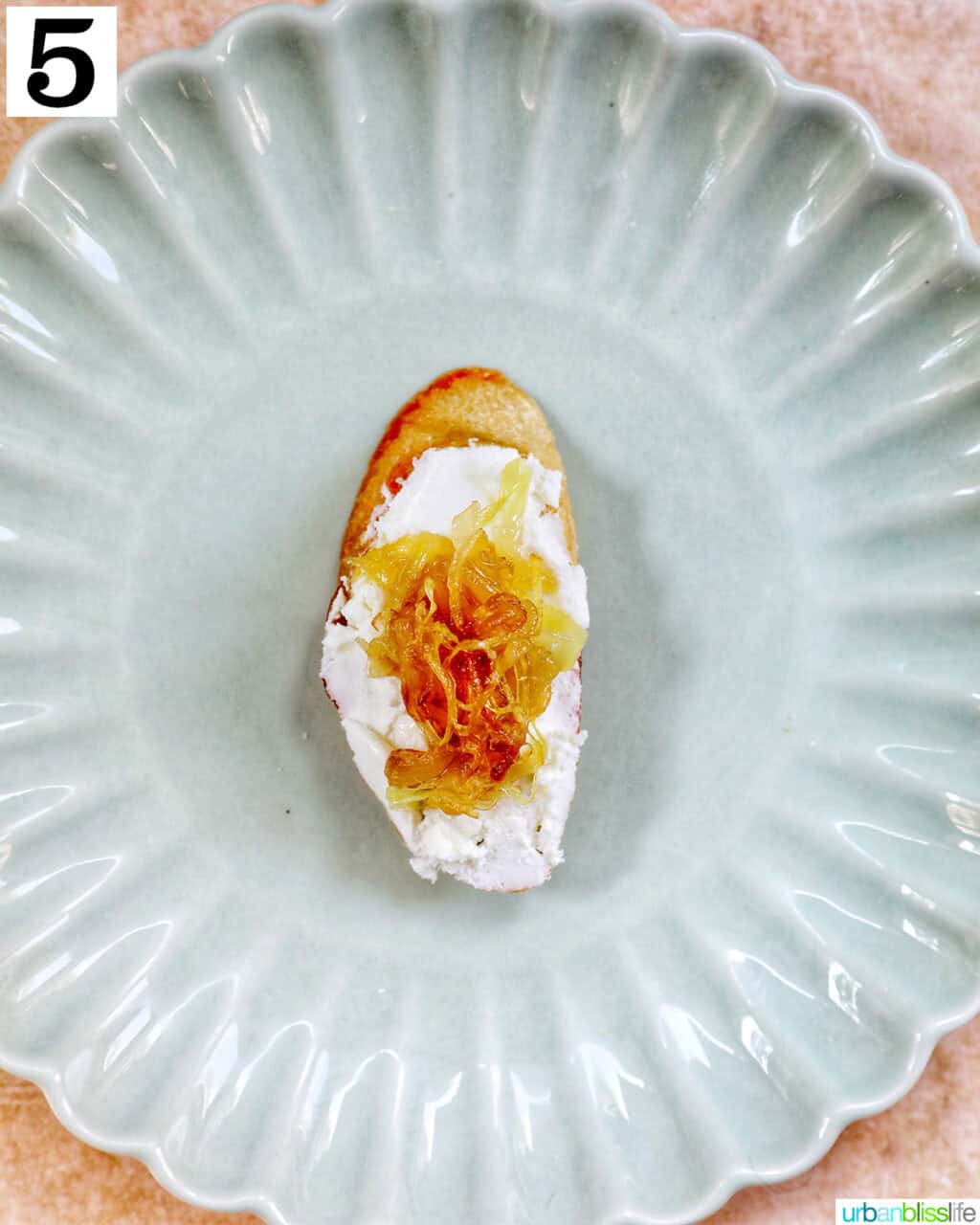 caramelized onions and goat cheese crostini slice on a green plate.