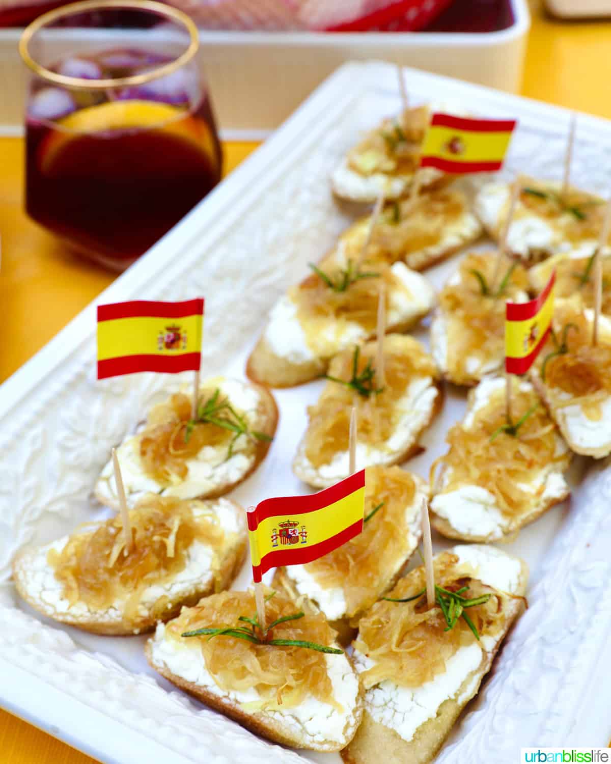 caramelized onions and goat cheese crostini on a plate with rosemary sprig garnish.