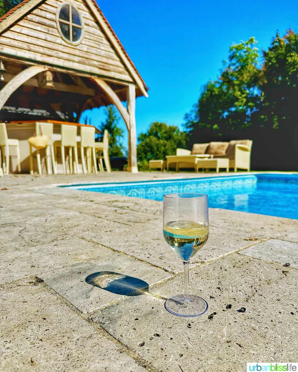glass of wine by a pool and pool bar at Chateau de Valcreuse in La Roche-Posay, France.