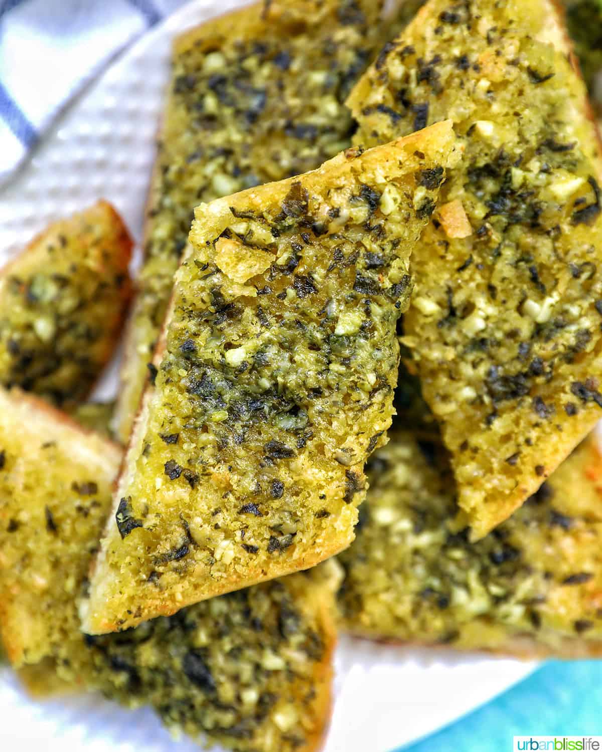 slices of pesto bread on a white platter with garnish of basil.