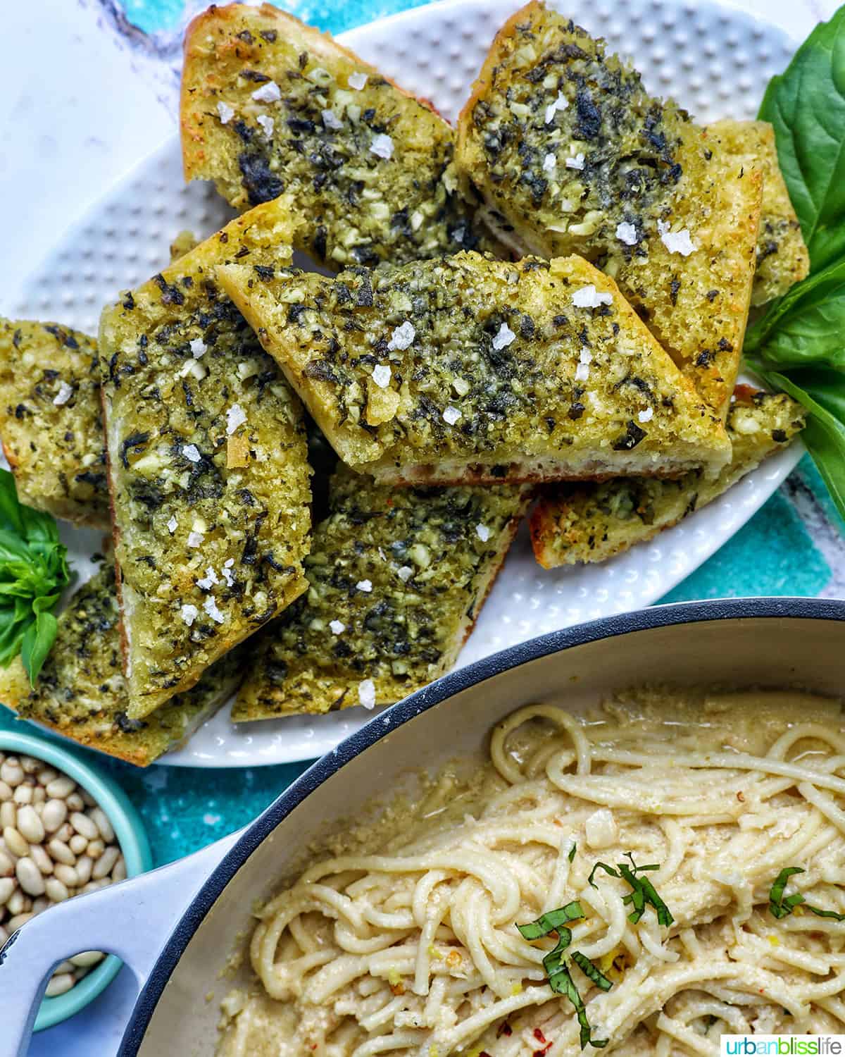 slices of pesto bread on a white platter with garnish of basil.