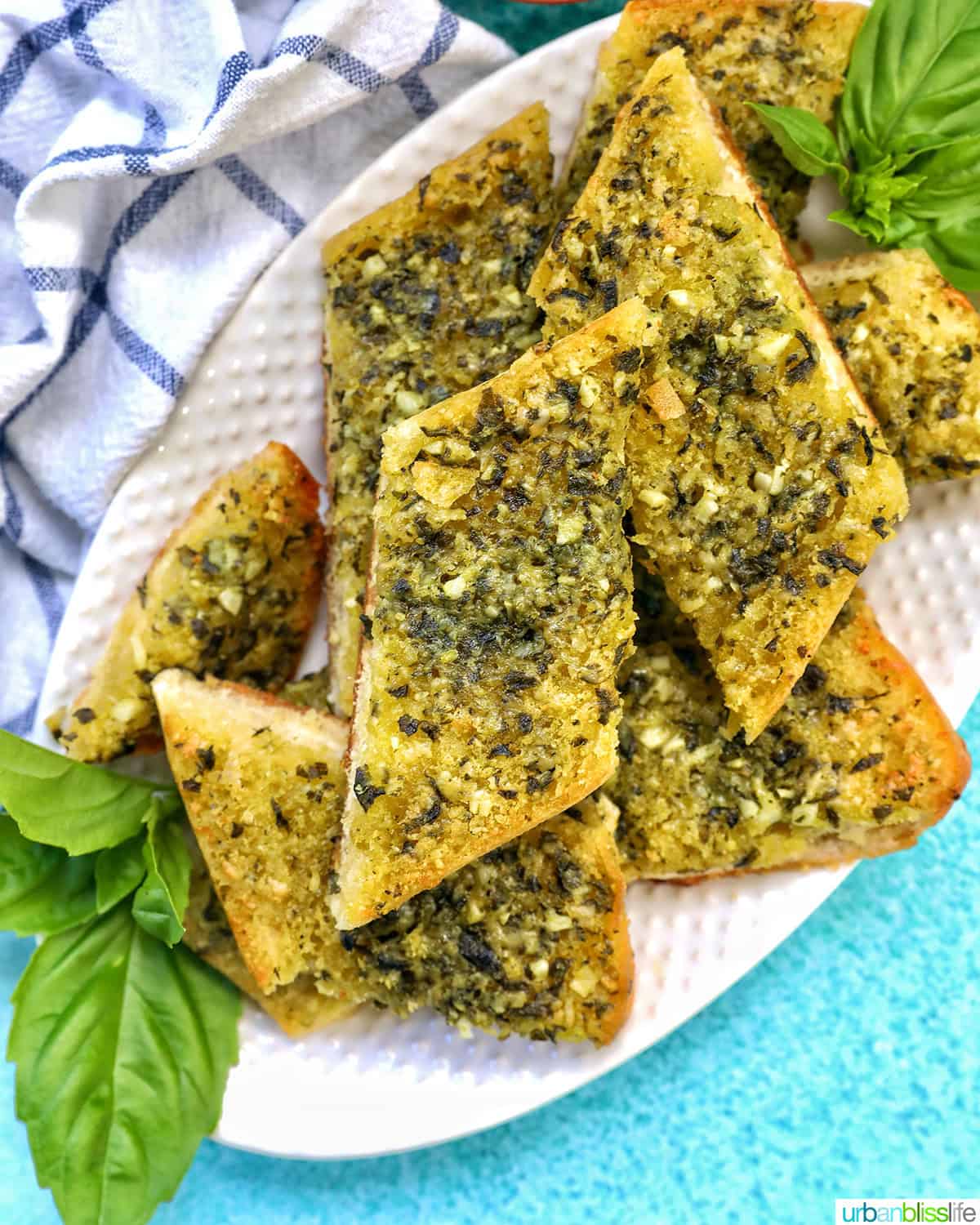 slices of pesto bread on a white platter with garnish of basil.