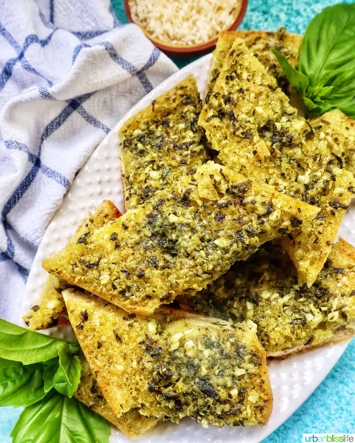 slices of pesto bread on a white platter with garnish of basil.