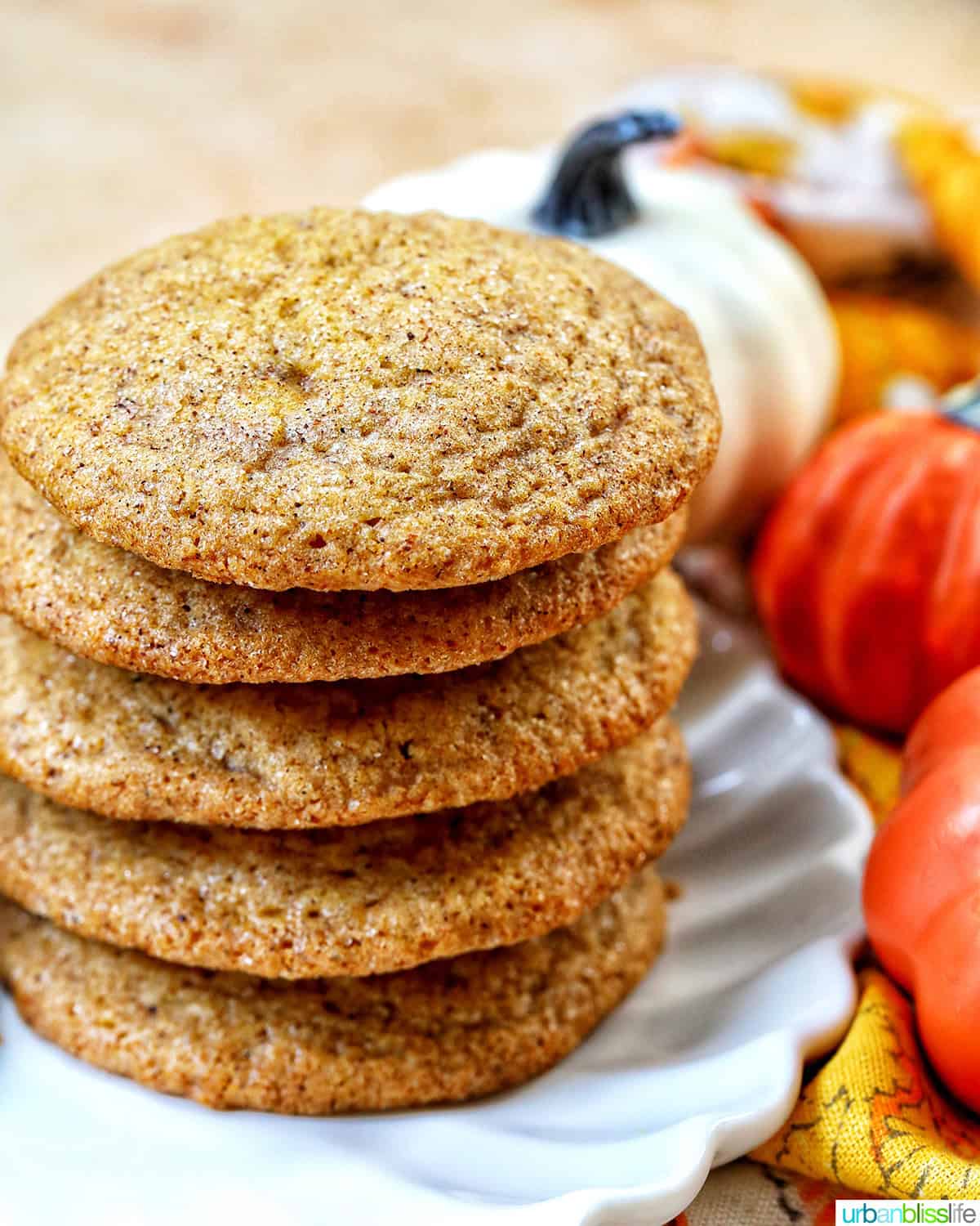 stack of pumpkin spice cookies with pumpkin decorations and cinnamon sticks.