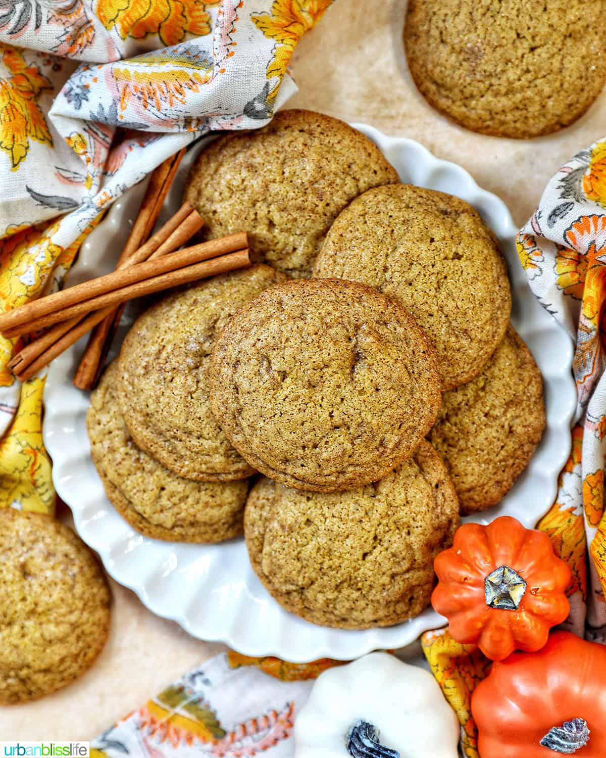 plate full of pumpkin spice cookies with pumpkin decorations and cinnamon sticks.