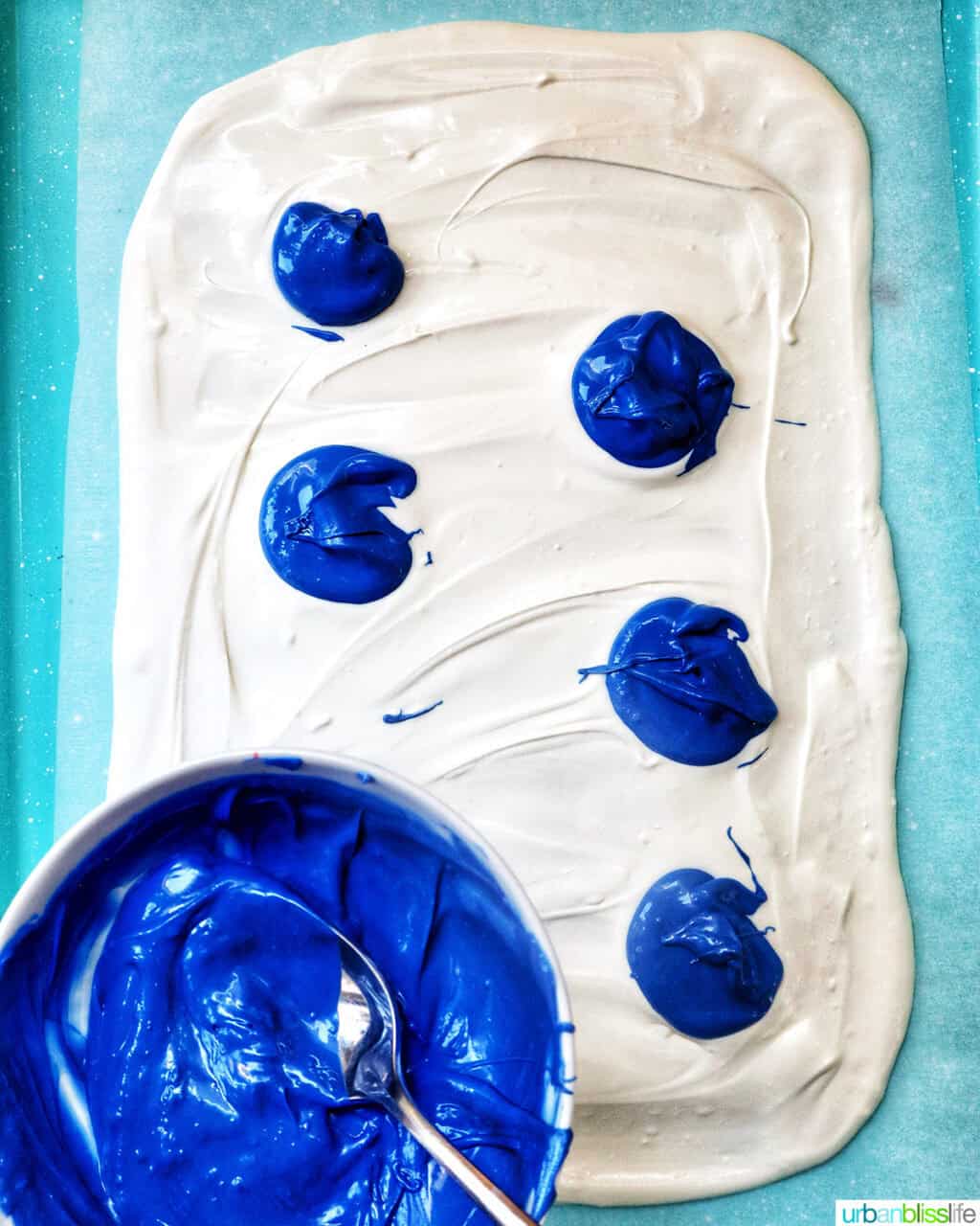 melted white chocolate and blue melted chocolate on a baking sheet.