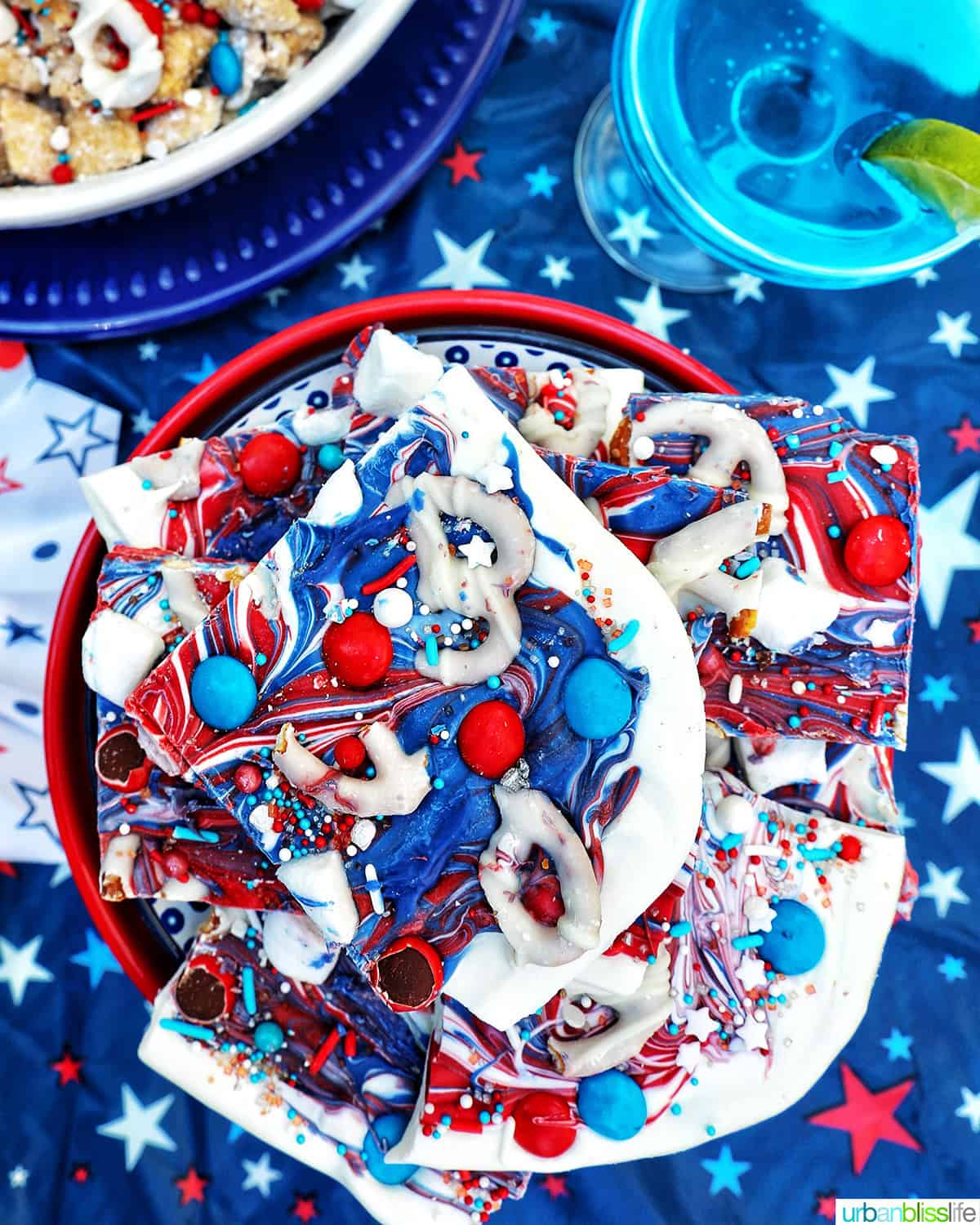 bowl of a stack of red, white, and blue bark next to a blue cocktail.