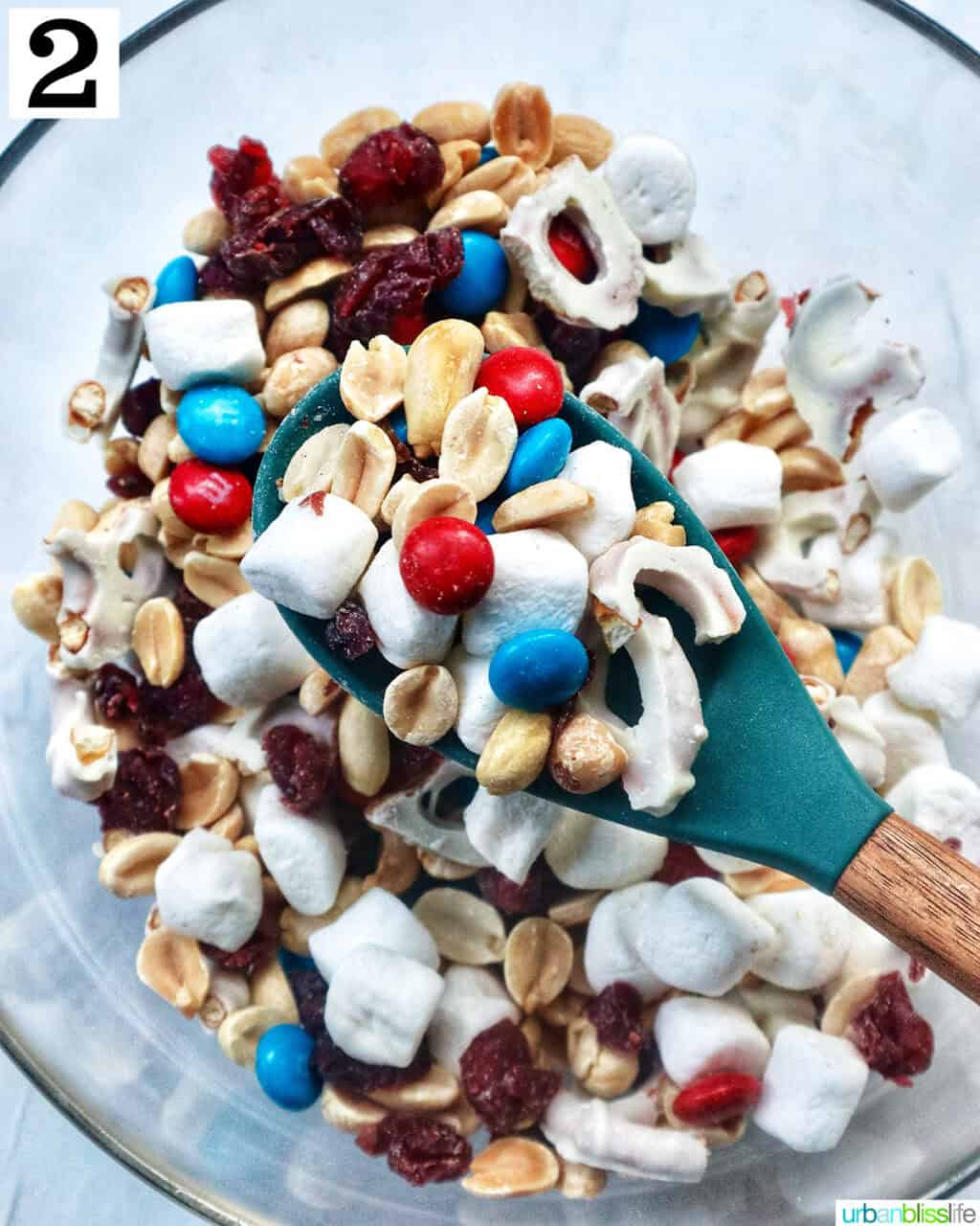 spoon full of red, white, and blue trail mix over a bowl of trail mix.