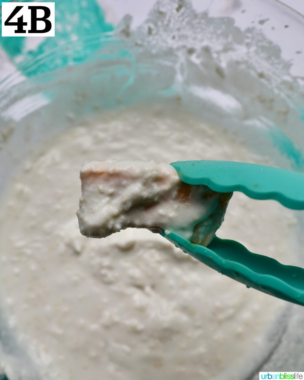 tongs holding plaintain dipped in batter over a bowl.