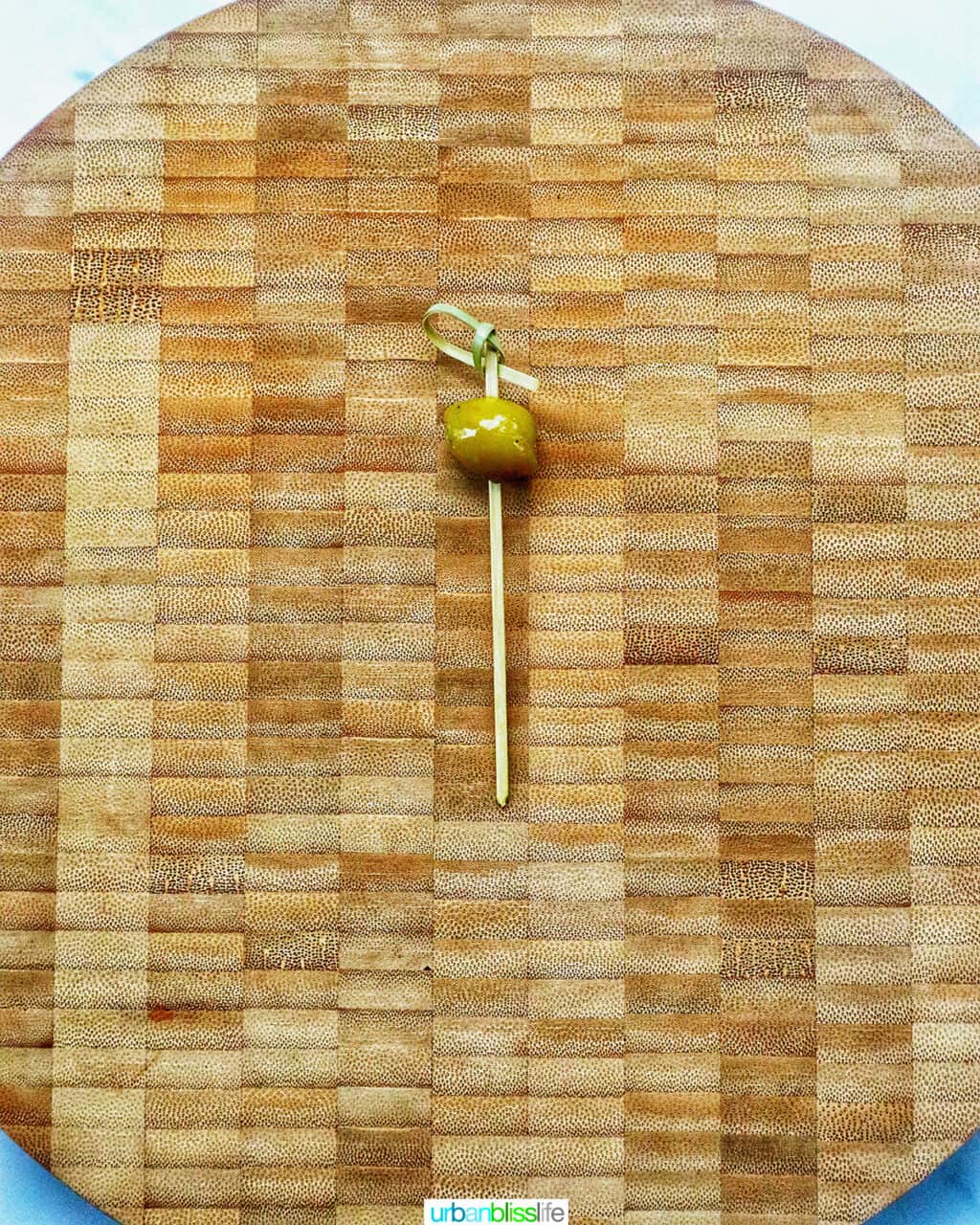 food pick with an olive on a cutting board.