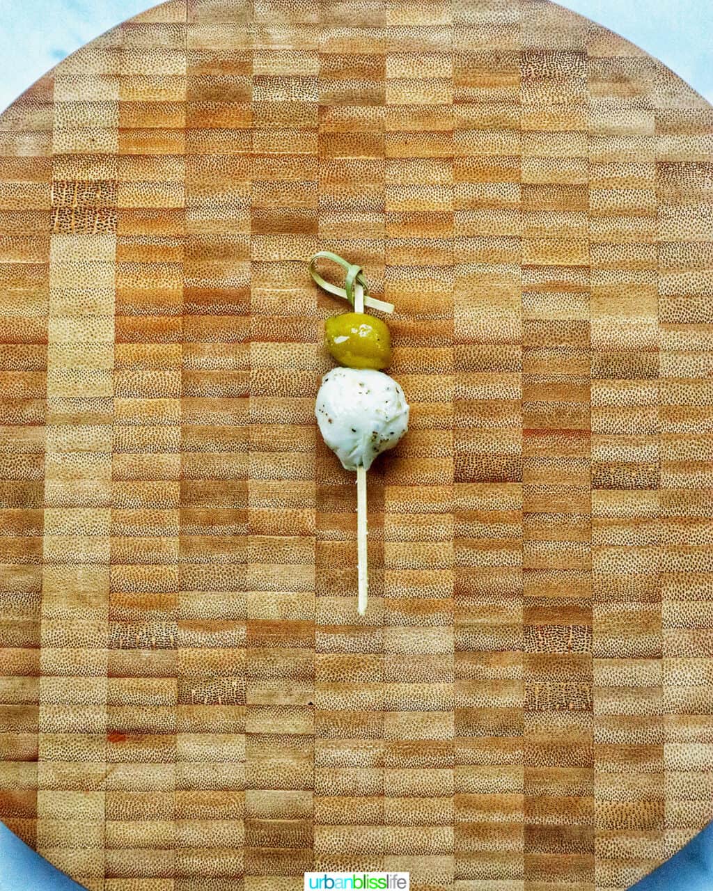 food pick with an olive and mozzarella ball on a cutting board.