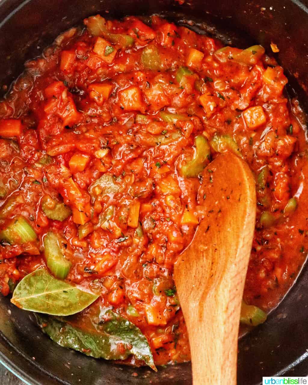 wooden spoon stirring sauce in a Dutch oven.