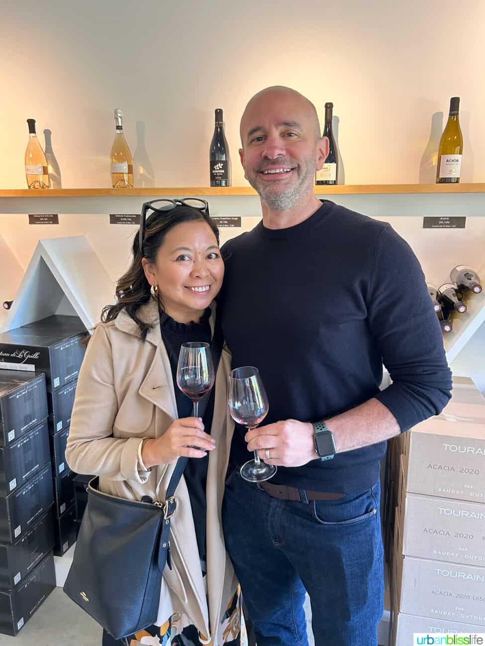 Marlynn Jayme Schotland and Alain Schotland holding wine glasses in the Chateau de la Grille wine tasting room in Chinon, France.