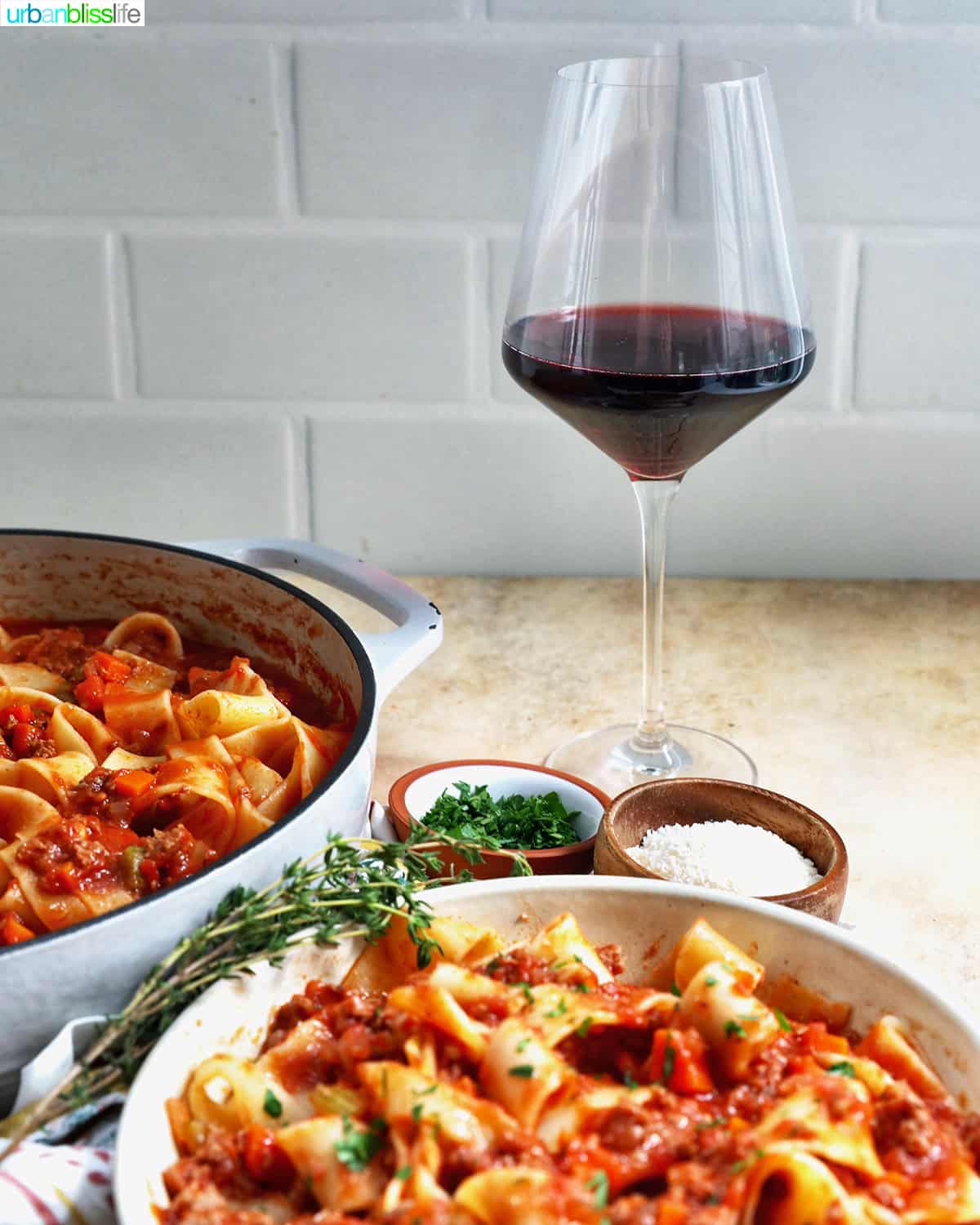bowl of lamb ragu pappardelle with glass of red wine.