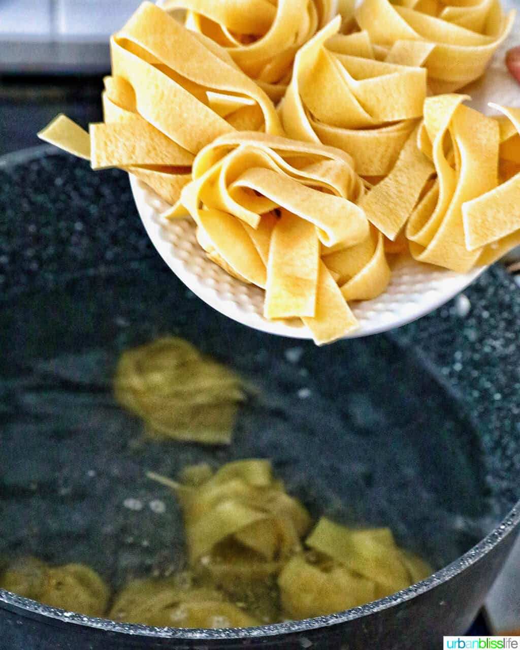 pappardelle noodles going into a large pot.