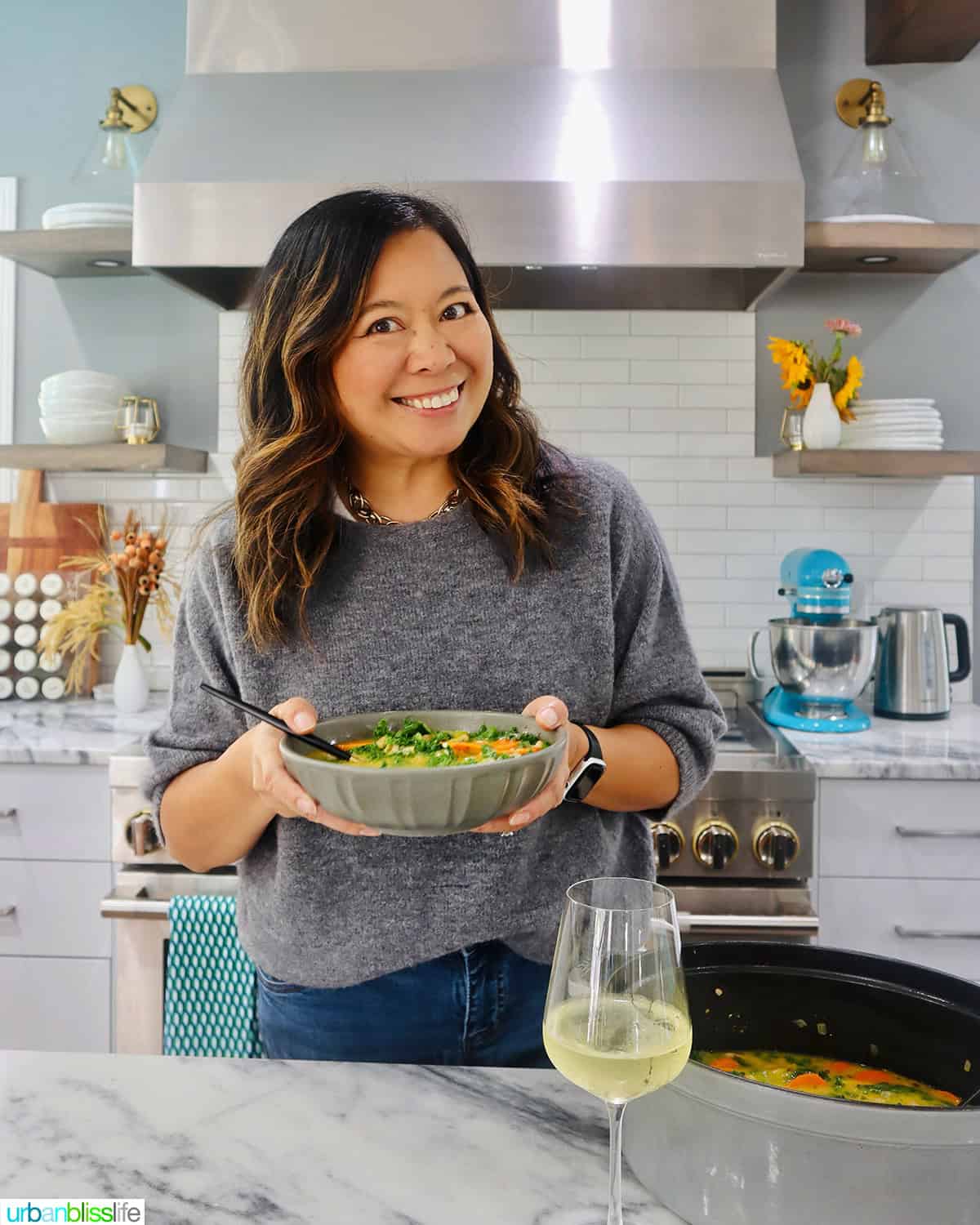 Marlynn Schotland holding a bowl of Tuscan kale and white bean soup in the kitchen.