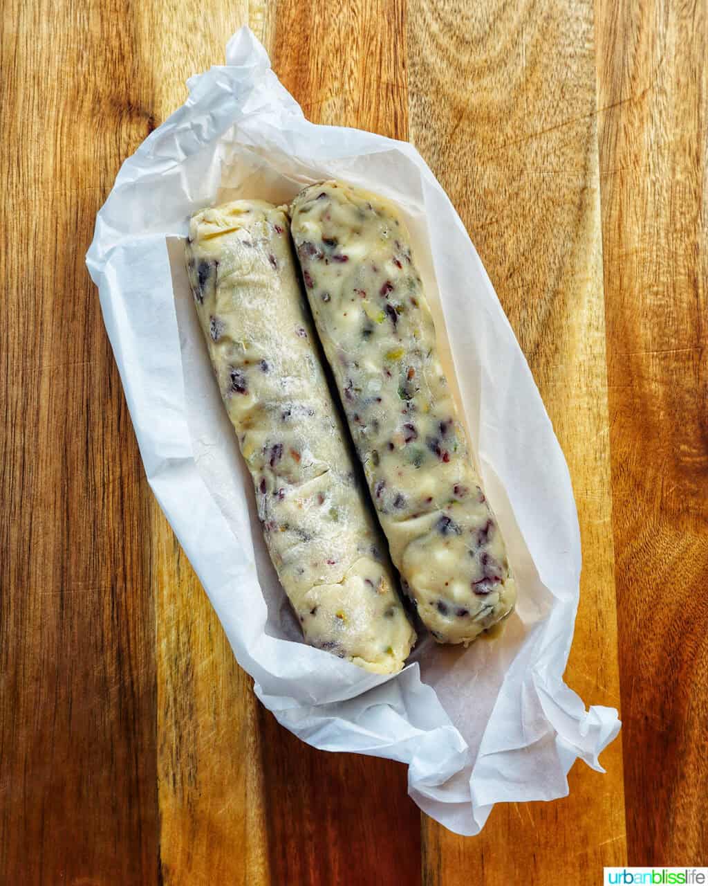 pistachio cranberry shortbread cookie dough rolled into logs on a cutting board.