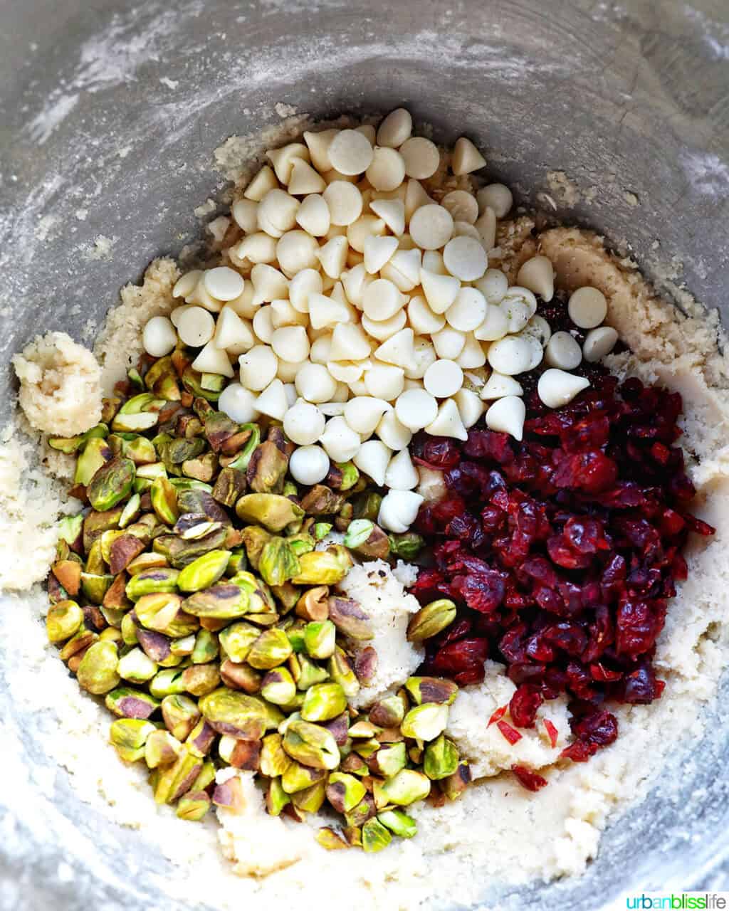 white chocolate chips, pistachios, and cranberries in a bowl to make pistachio cranberry shortbread cookie dough