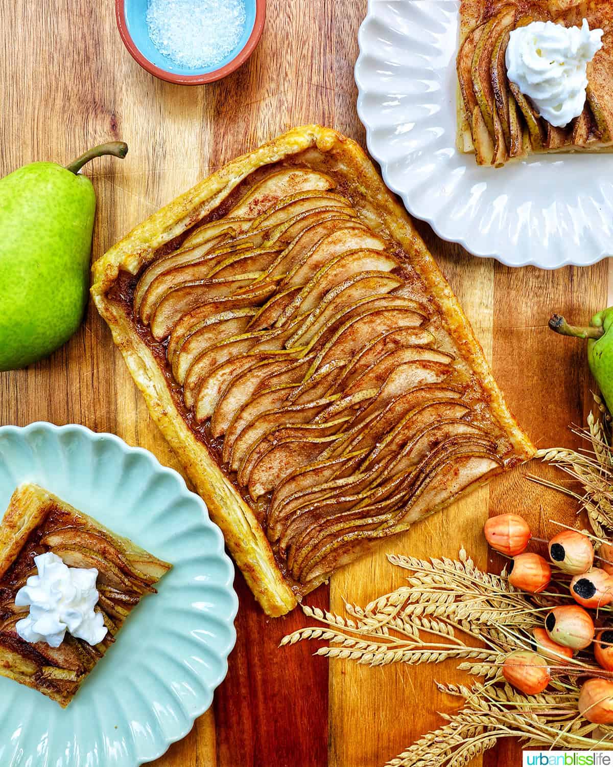 ginger and pear tart with puff pastry in the center, with plates of slices of pear tart.