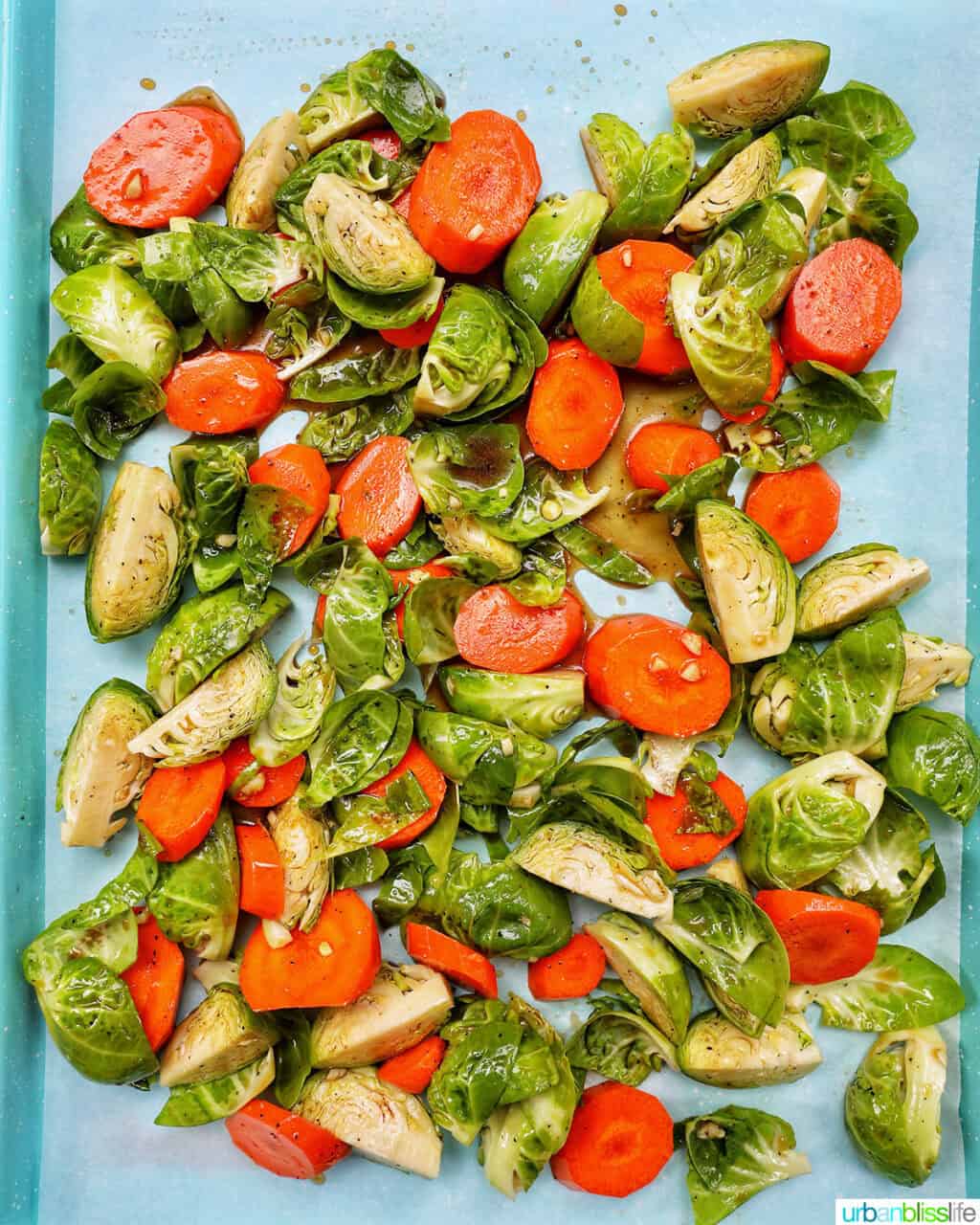 roasted brussels sprouts and carrot slices on a baking sheet.