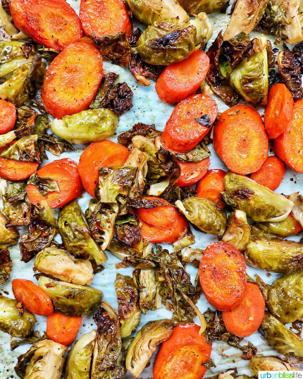 roasted brussels sprouts and carrot slices on a bakng sheet.