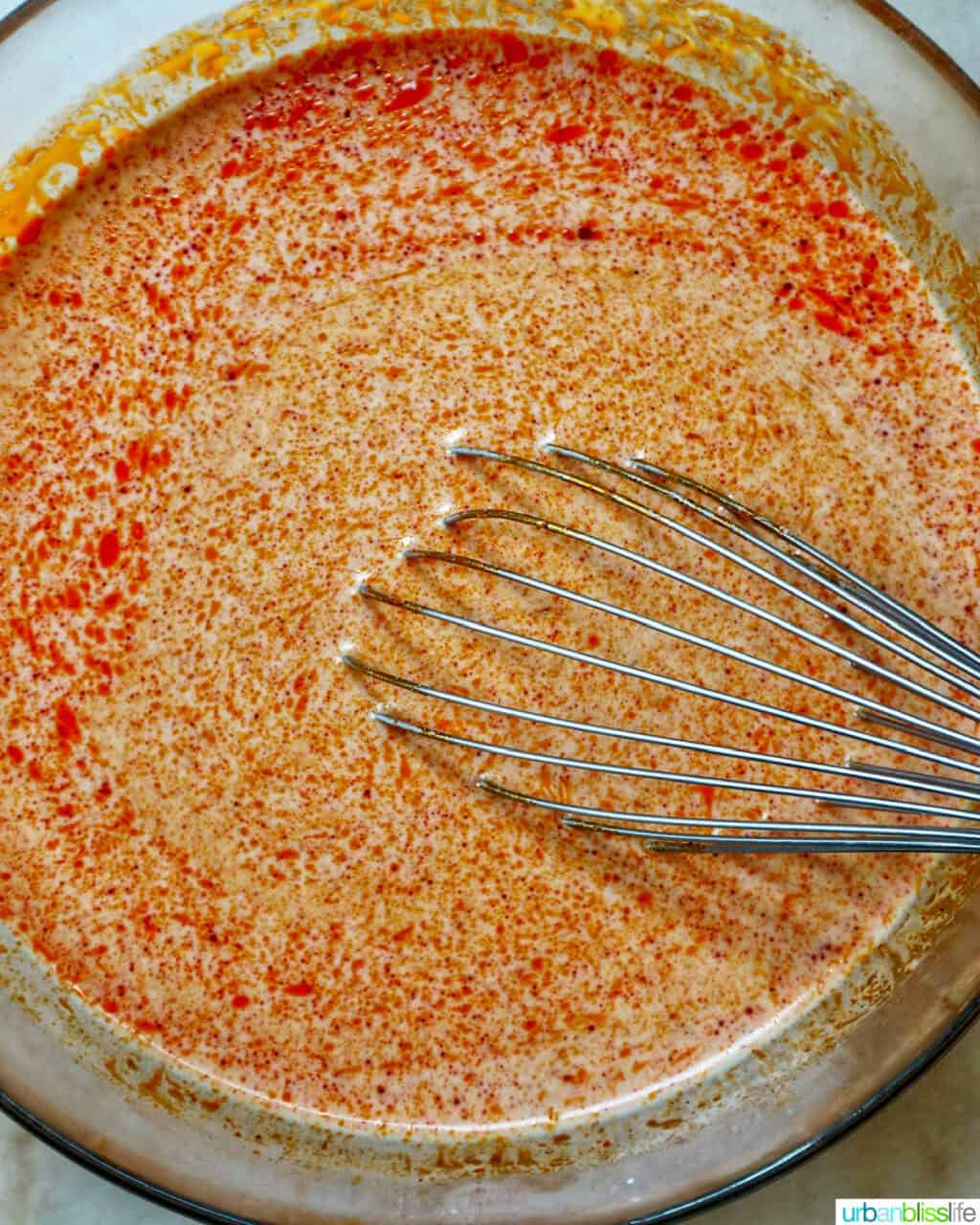 whisking curry sauce in a large bowl.