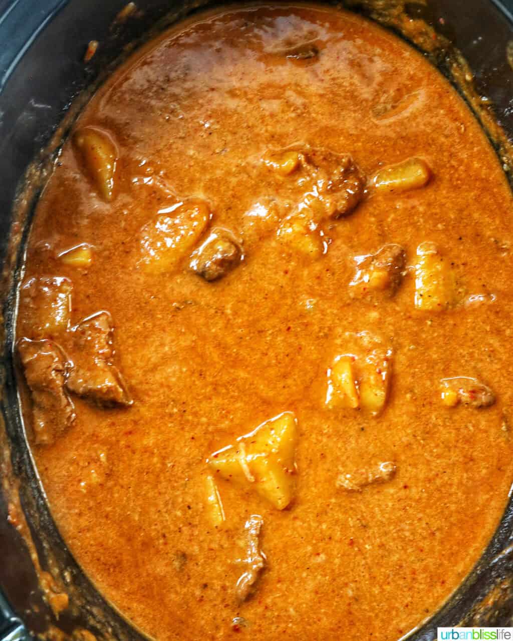 slow cooker beef massaman curry cooking in a crockpot slow cooker.