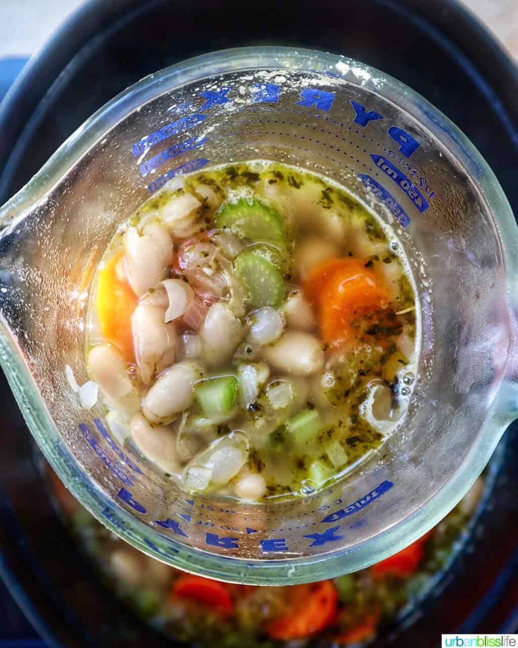 measuring cup of uscan kale and white bean soup ingredients.