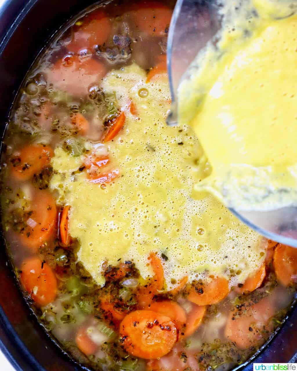 pouring blended soup back into the dutch oven of soup.