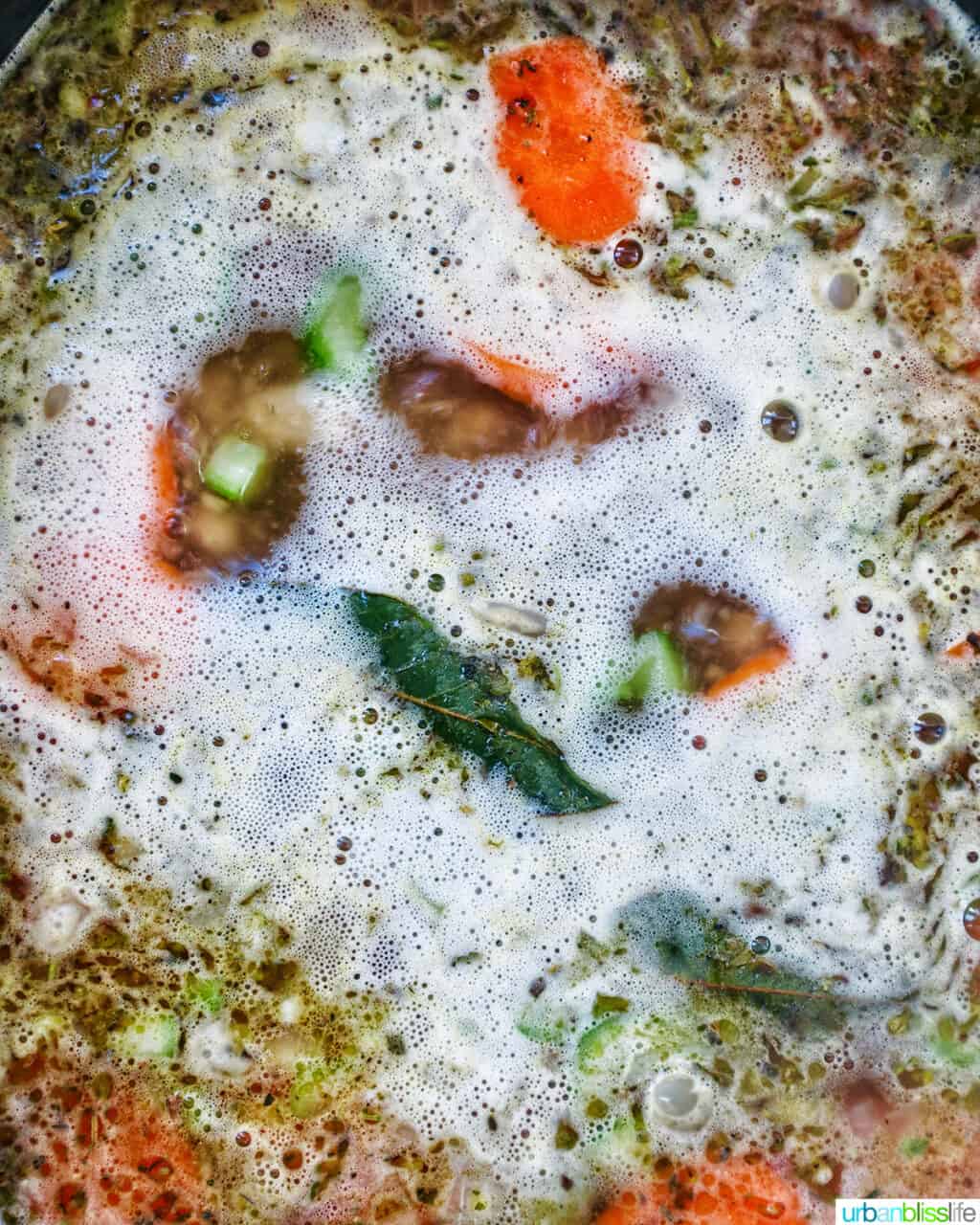 uscan kale and white bean soup boilng in a Dutch oven.