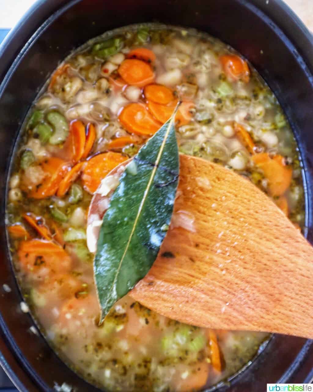 wooden spoon taking out bay leaves from soup.