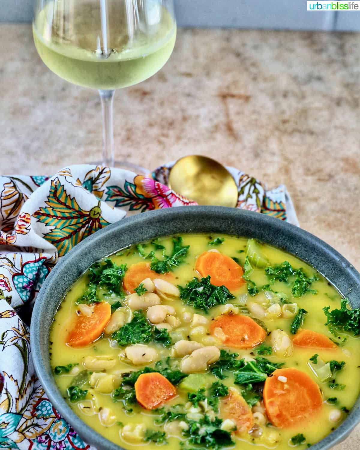 bowl of Tuscan kale and white bean soup with glass of white wine.