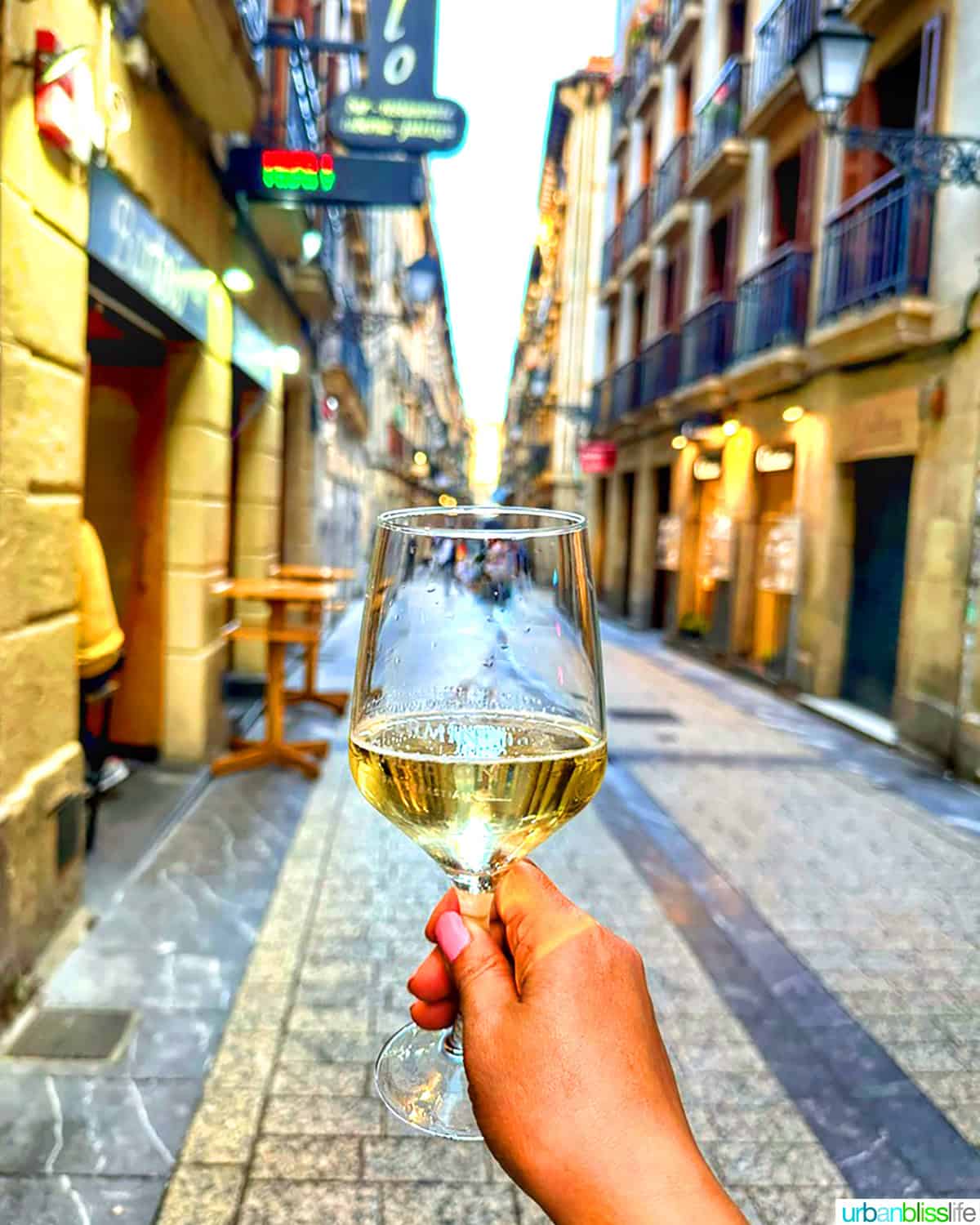 holding glass of txakoli wine in old town san sebastian, spain