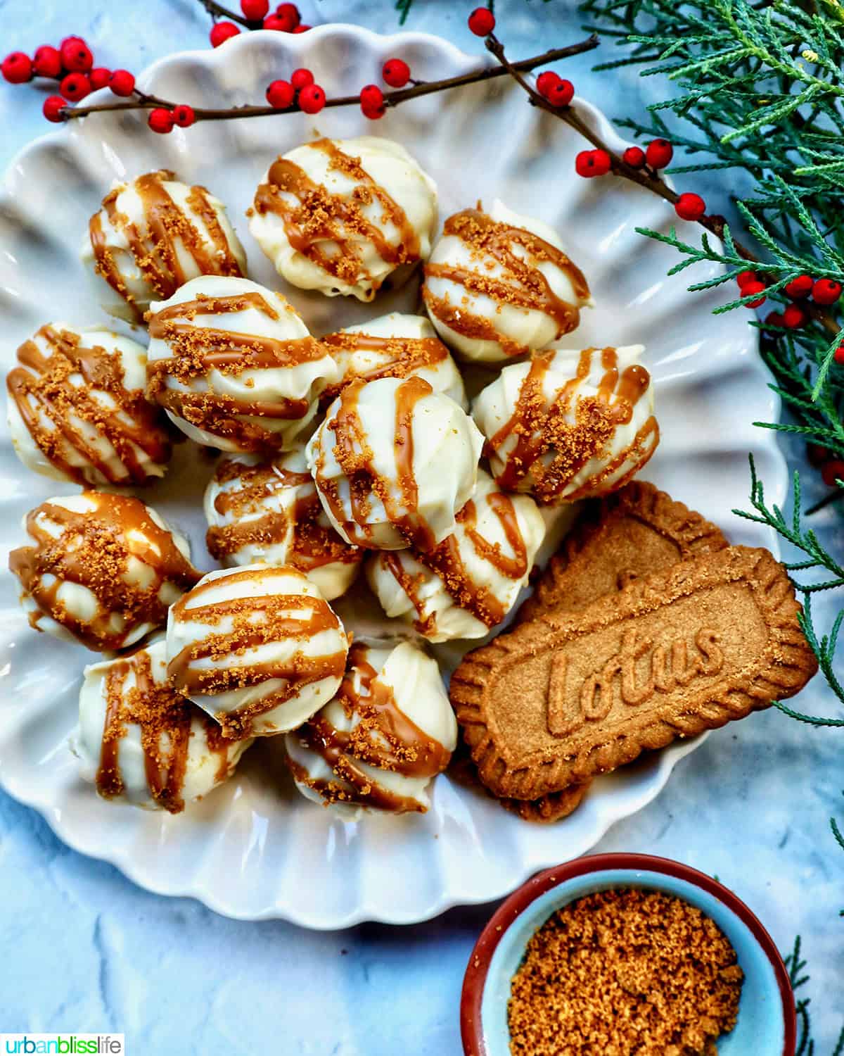 pile of Biscoff truffles on a plate with Biscoff cookies and holiday decorations.