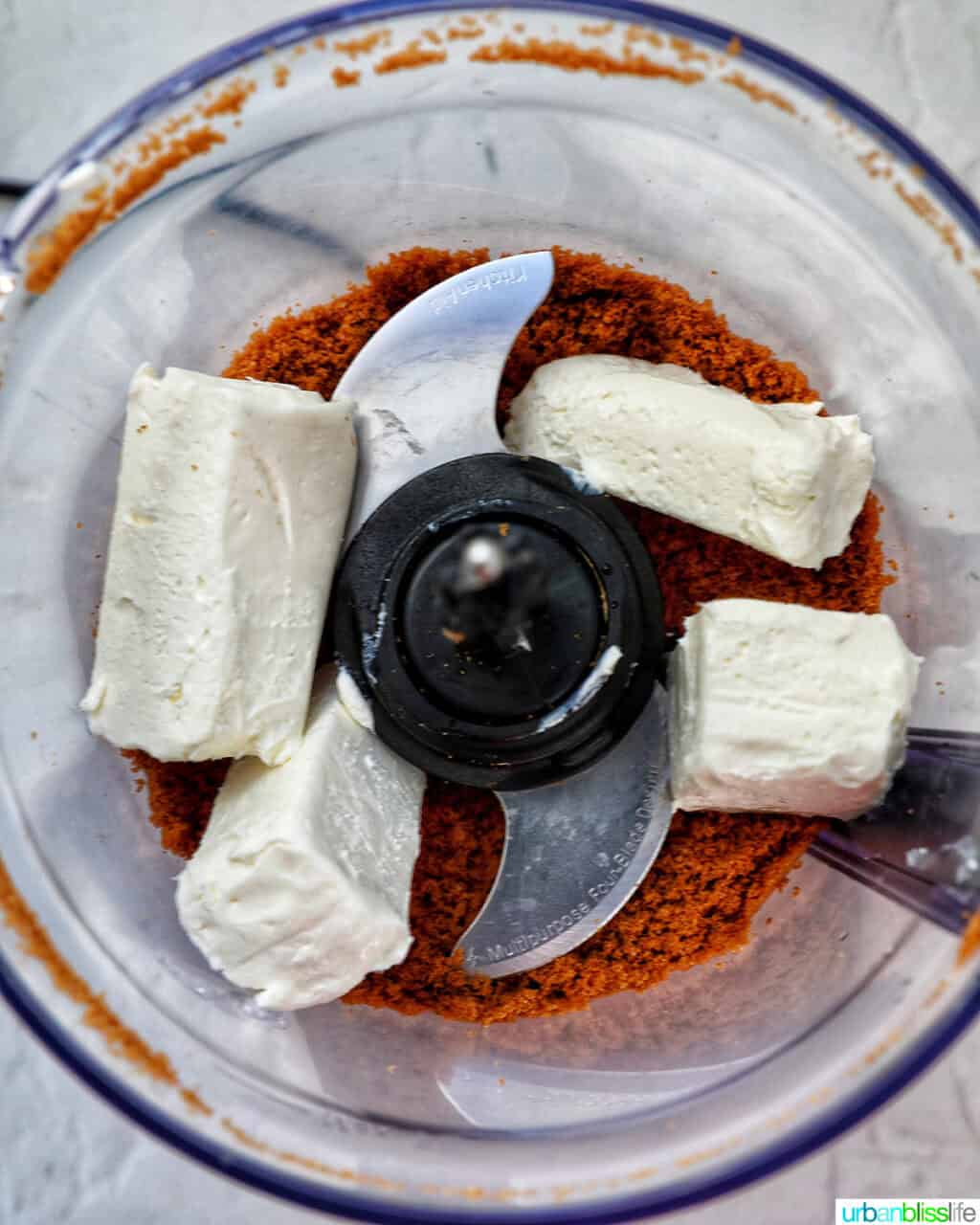 cream cheese addeed to Biscoff cookie crumbles in a food processor.