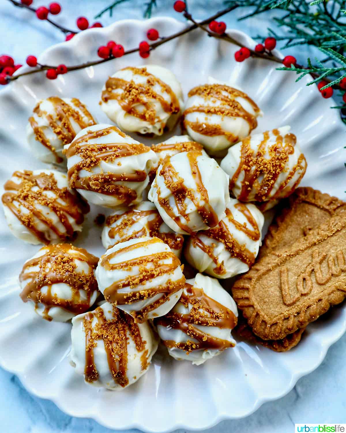 pile of Biscoff truffles on a plate with Biscoff cookies and holiday decorations.