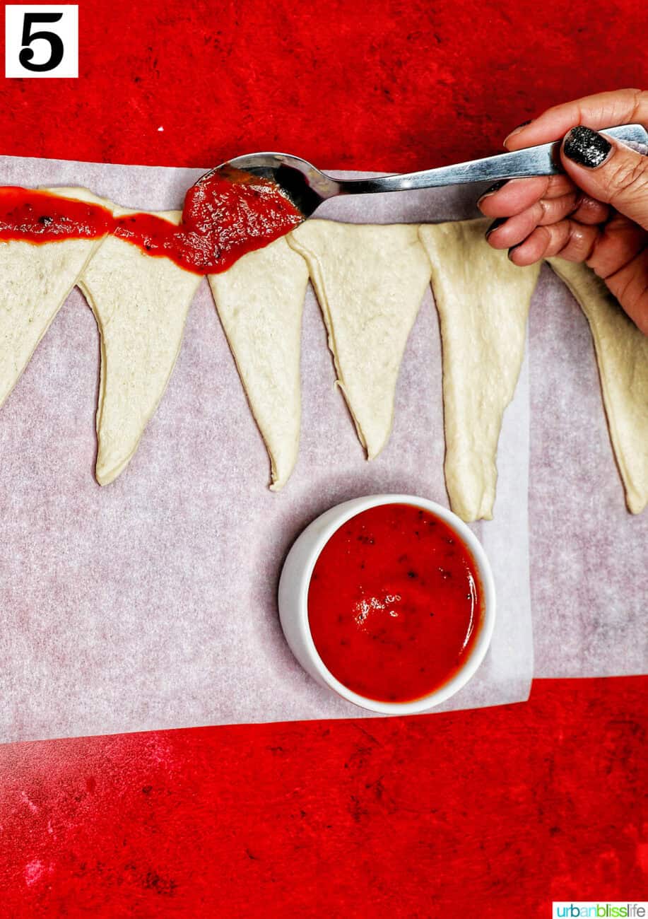 adding pizza sauce to candy cane pizza dough.
