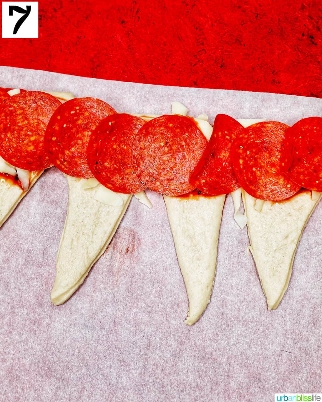 adding pepperoni onto triangles of pizza dough.
