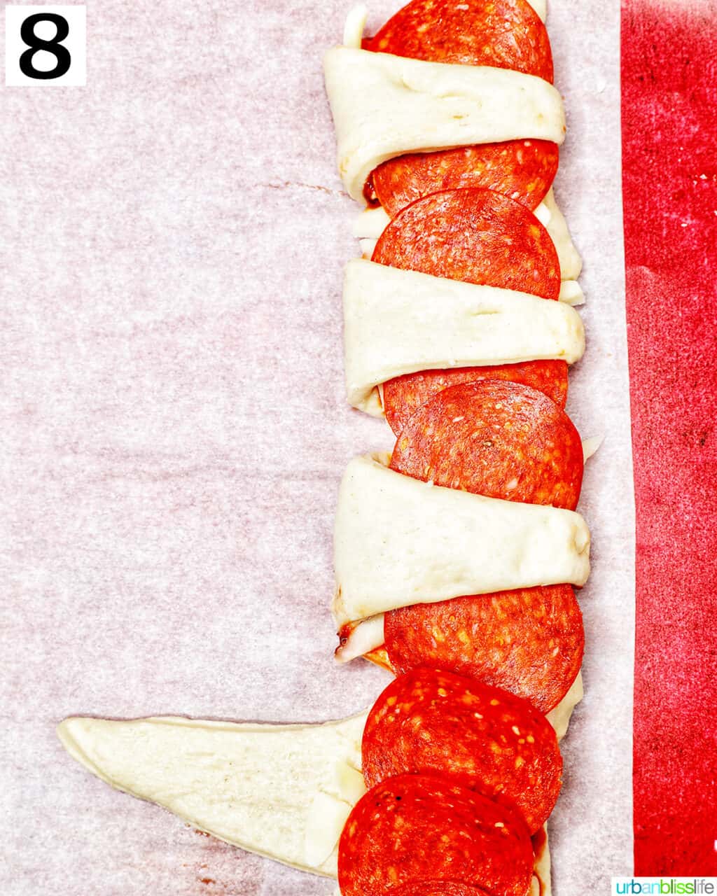 folding pizza dough triangles over pepperoni.