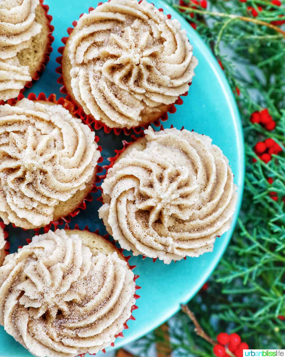 cinnamon cupcakes on a blue cake pedestal and holiday decorations.