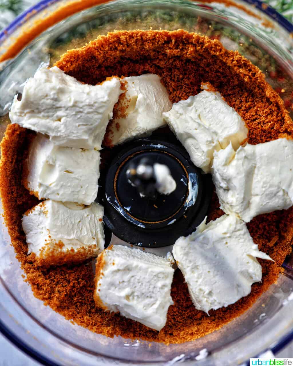 cream cheese added to gingerbread cookie crumbles in a food processor.