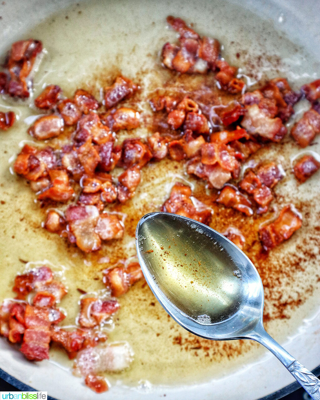 spoon removing bacon grease from pan.