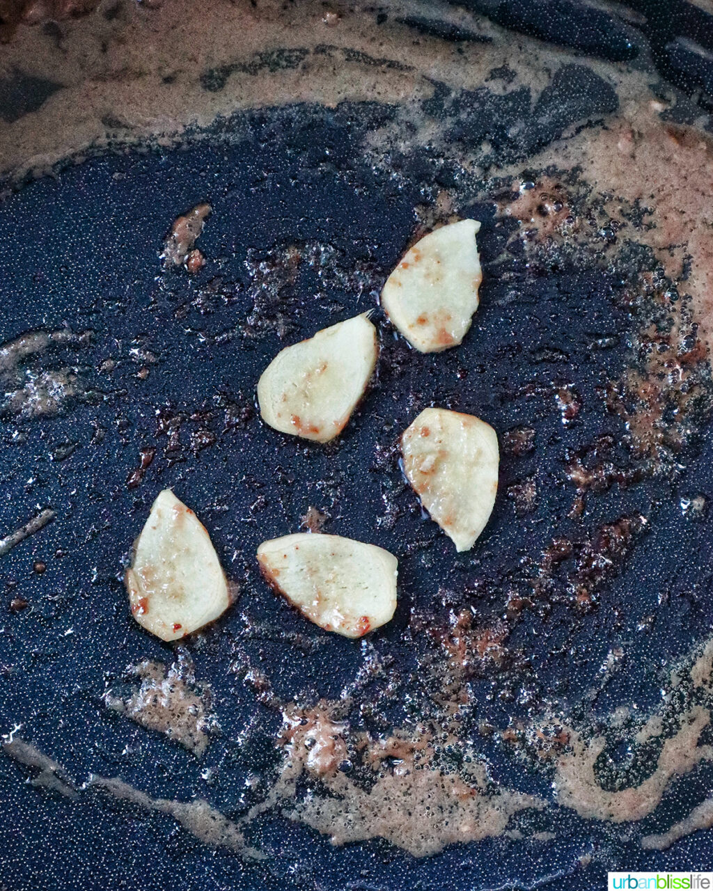 sliced ginger sauteing in a pan.