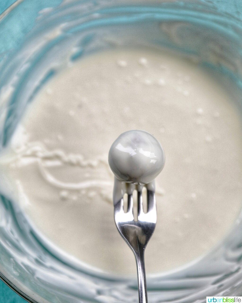 fork dipping a birthday cake truffle into melted white chocolate.