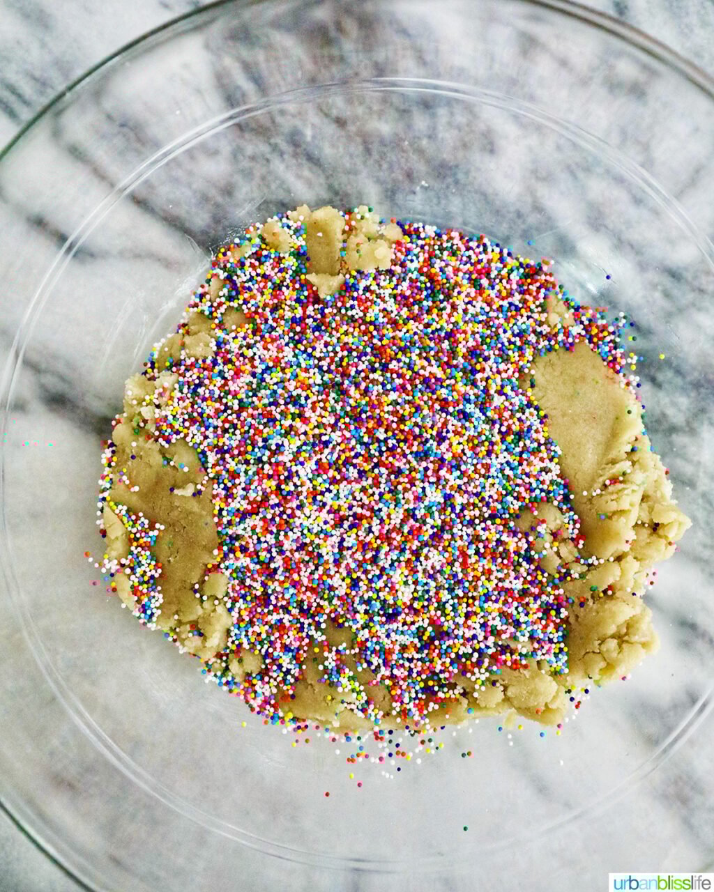 sprinkles and birthday cake truffle dough in a glass bowl.