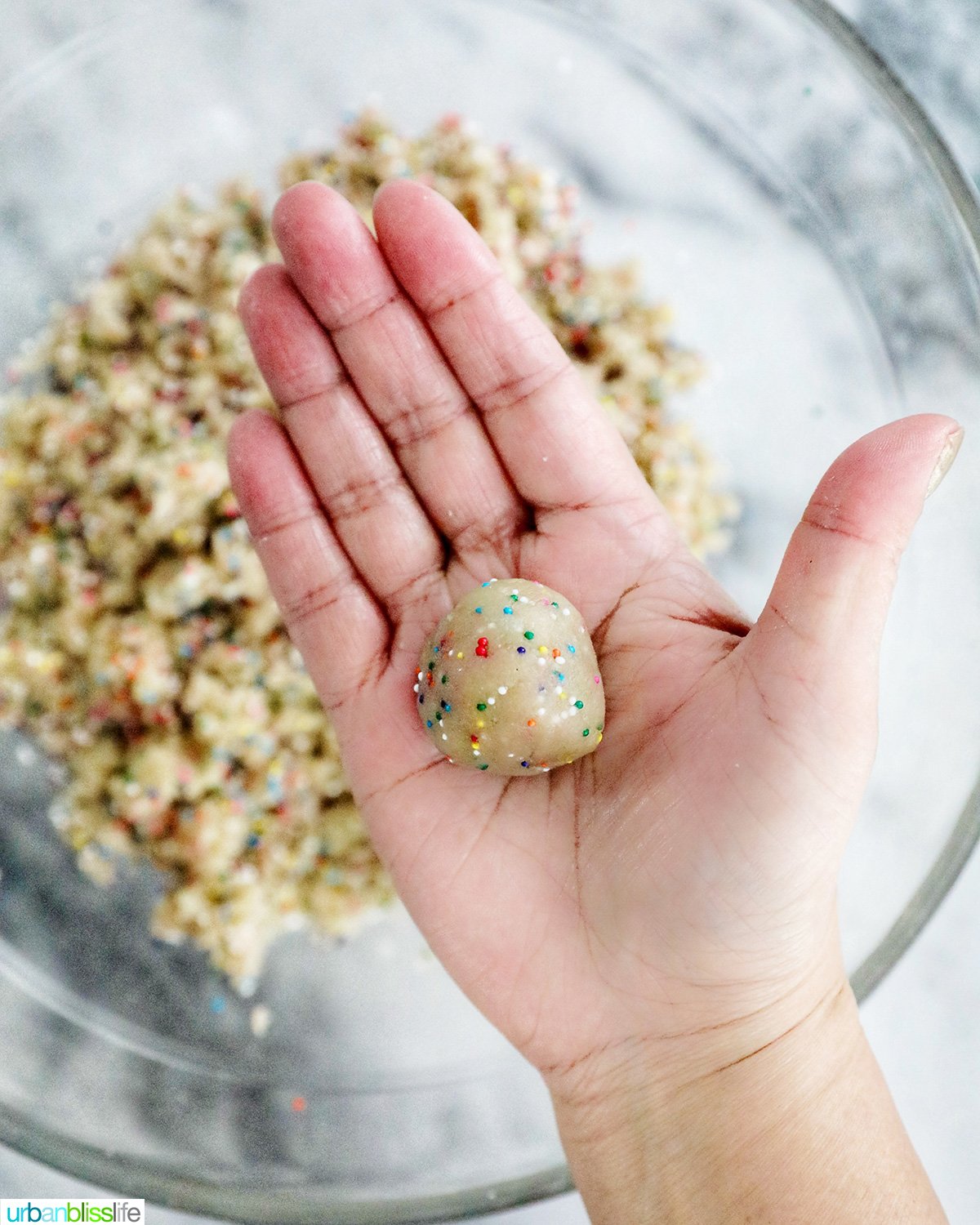 ball of birthday cake truffle dough in a hand.